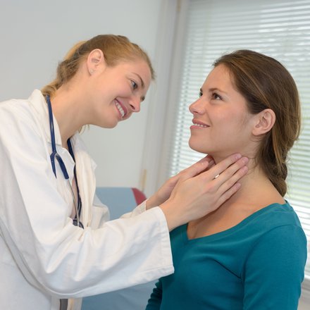 Ärztin untersucht den Hals einer Patientin